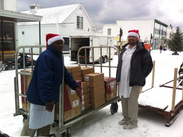 Fudge makers Carnel and Ricardo fill a luggage cart full of Murdick's of Mackinac headed for the Arnold Line dock and FedEx delivery.